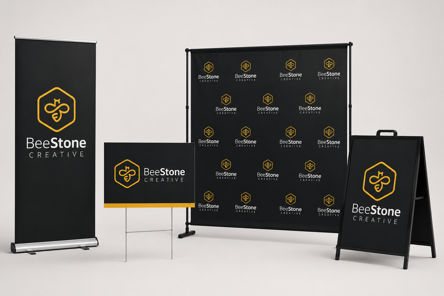 Display setup with banners and signs for BeeStone Creative featuring black backgrounds with yellow and white text and logos.