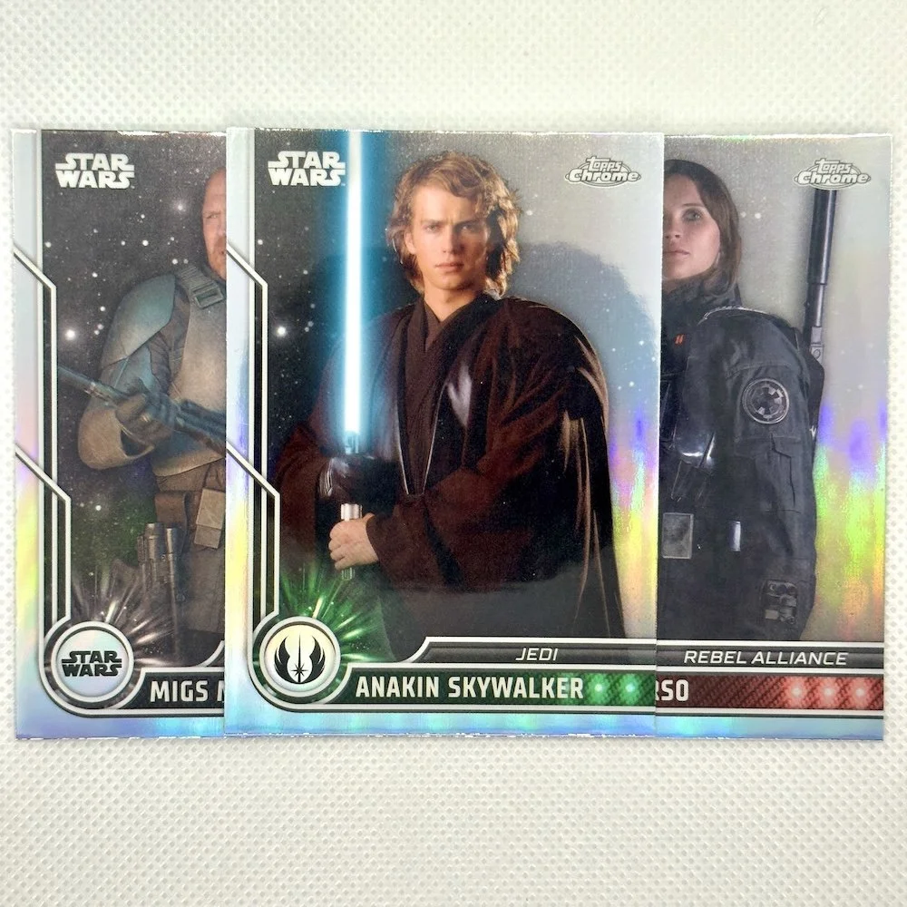 Three Star Wars trading cards featuring Migs Mayfeld, Anakin Skywalker, and Fennec Shand, with colorful holographic effects.