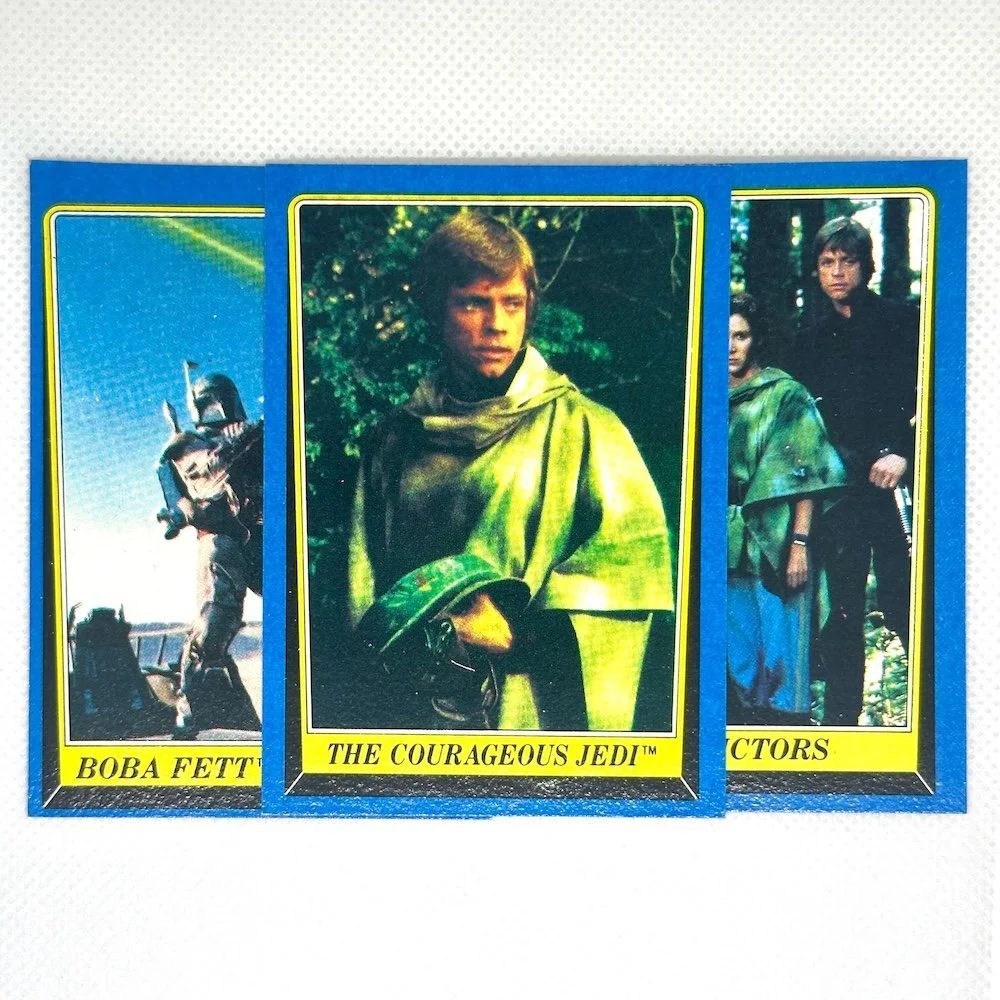 Three vintage Star Wars trading cards featuring characters Boba Fett, Luke Skywalker as The Courageous Jedi, and another character, set on a white background.