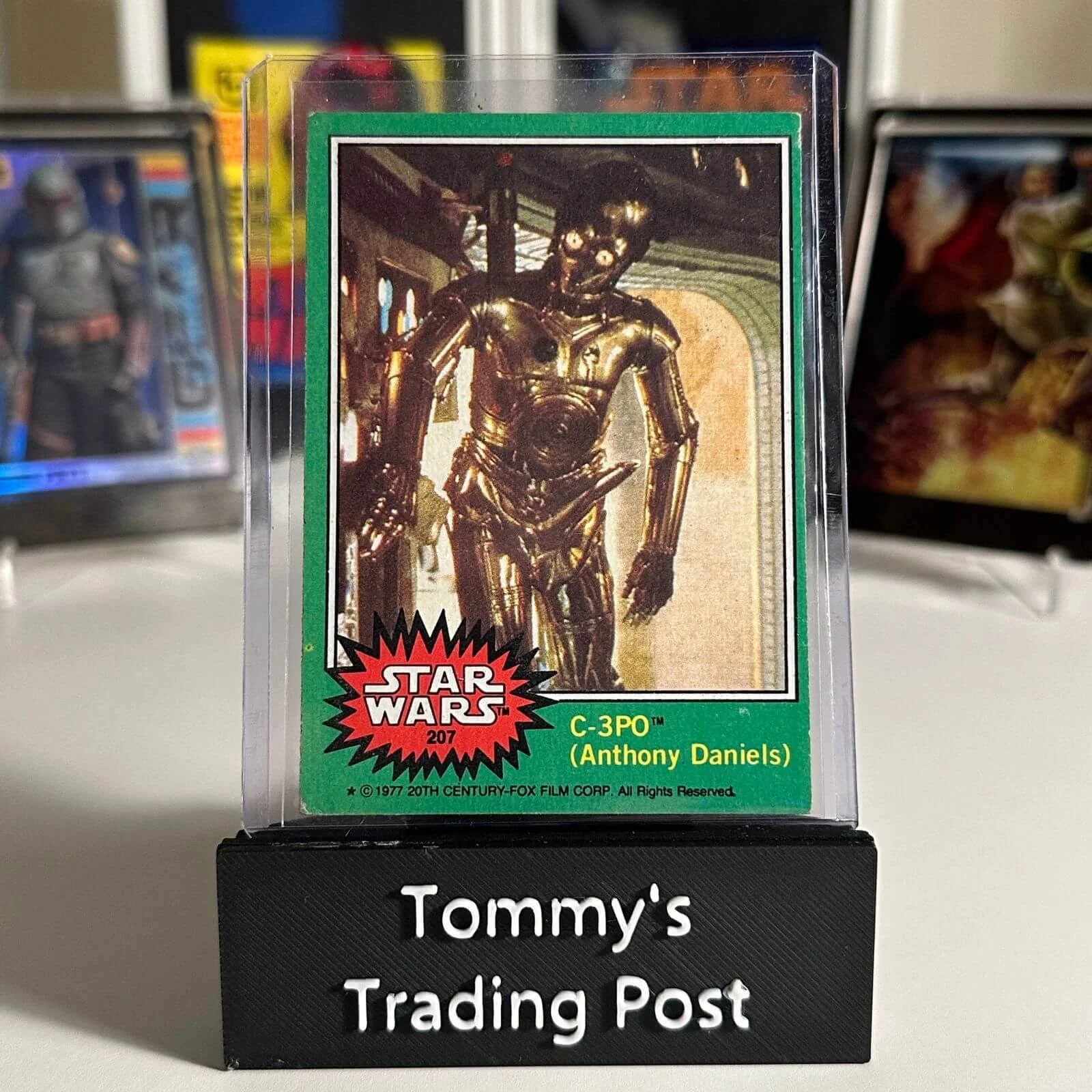 Star Wars C-3PO trading card featuring Anthony Daniels, displayed on a sign reading 'Tommy's Trading Post'.