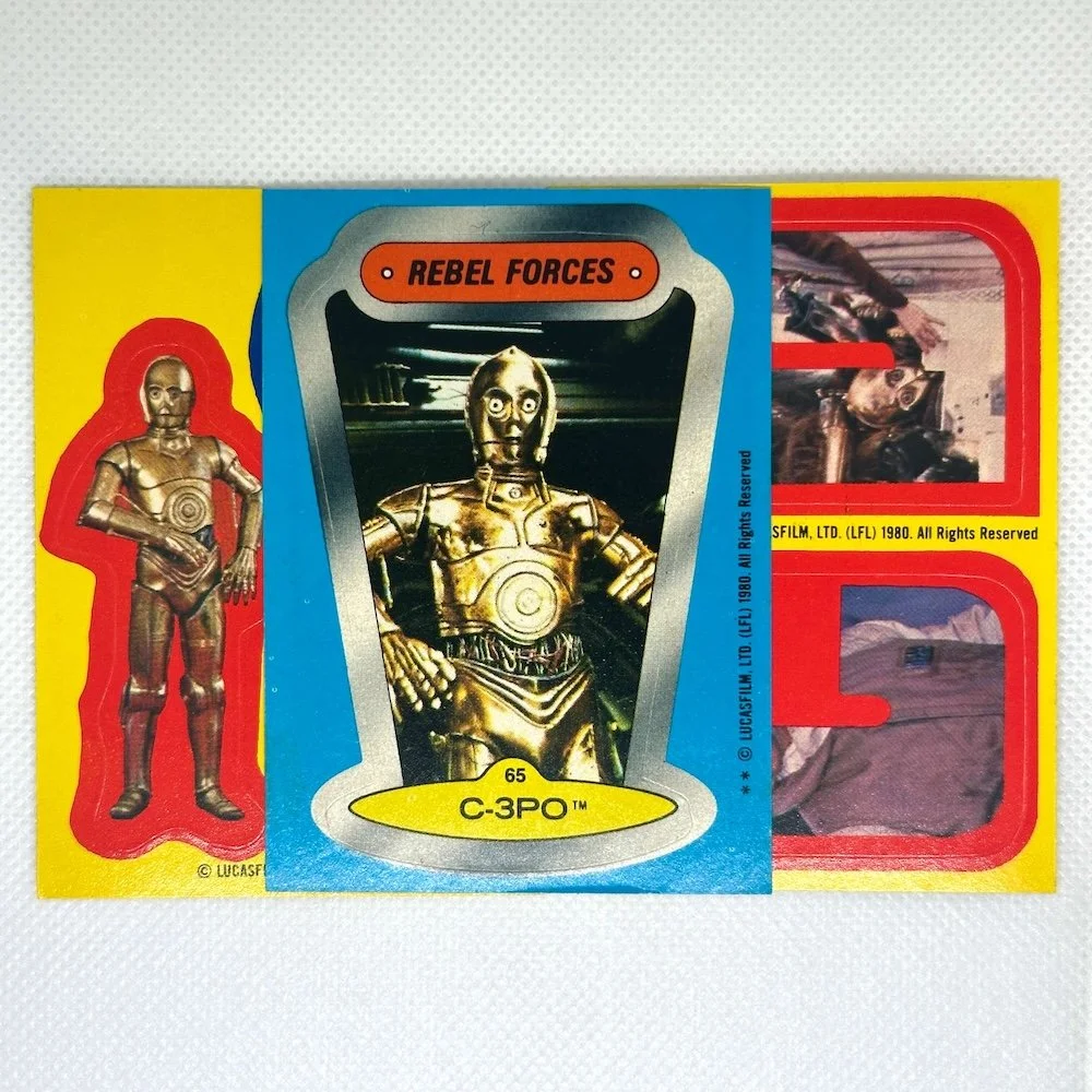 Star Wars C-3PO toy figure and packaging from the 1980 film release along with two movie scene photos on the packaging.