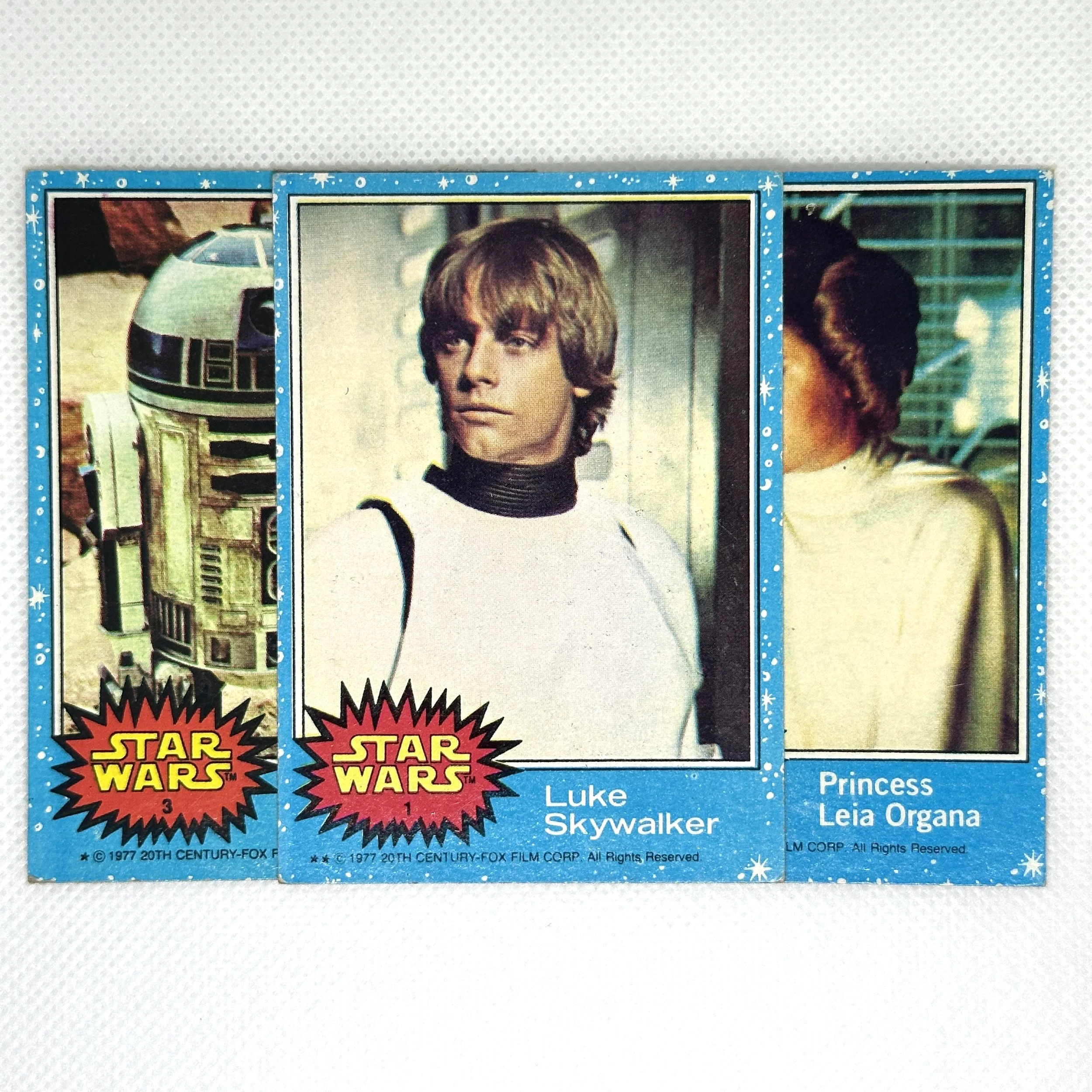 Three vintage Star Wars collector cards featuring characters R2-D2, Luke Skywalker, and Princess Leia Organa.