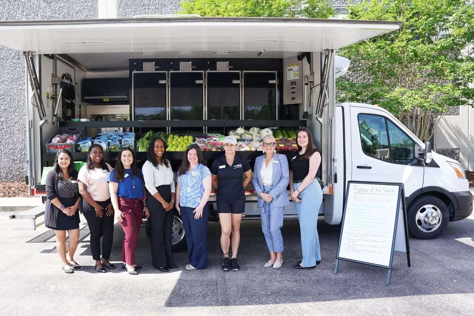 A group of people poses in front of a mobile market truck at the launch