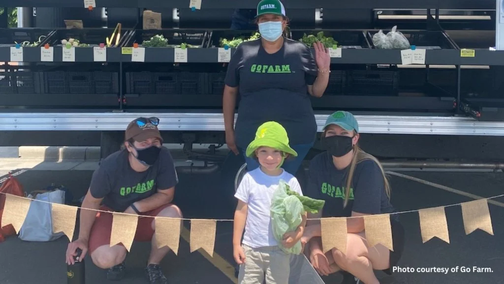 GoFarm workers and child posing in front of GoFarm mobile market truck