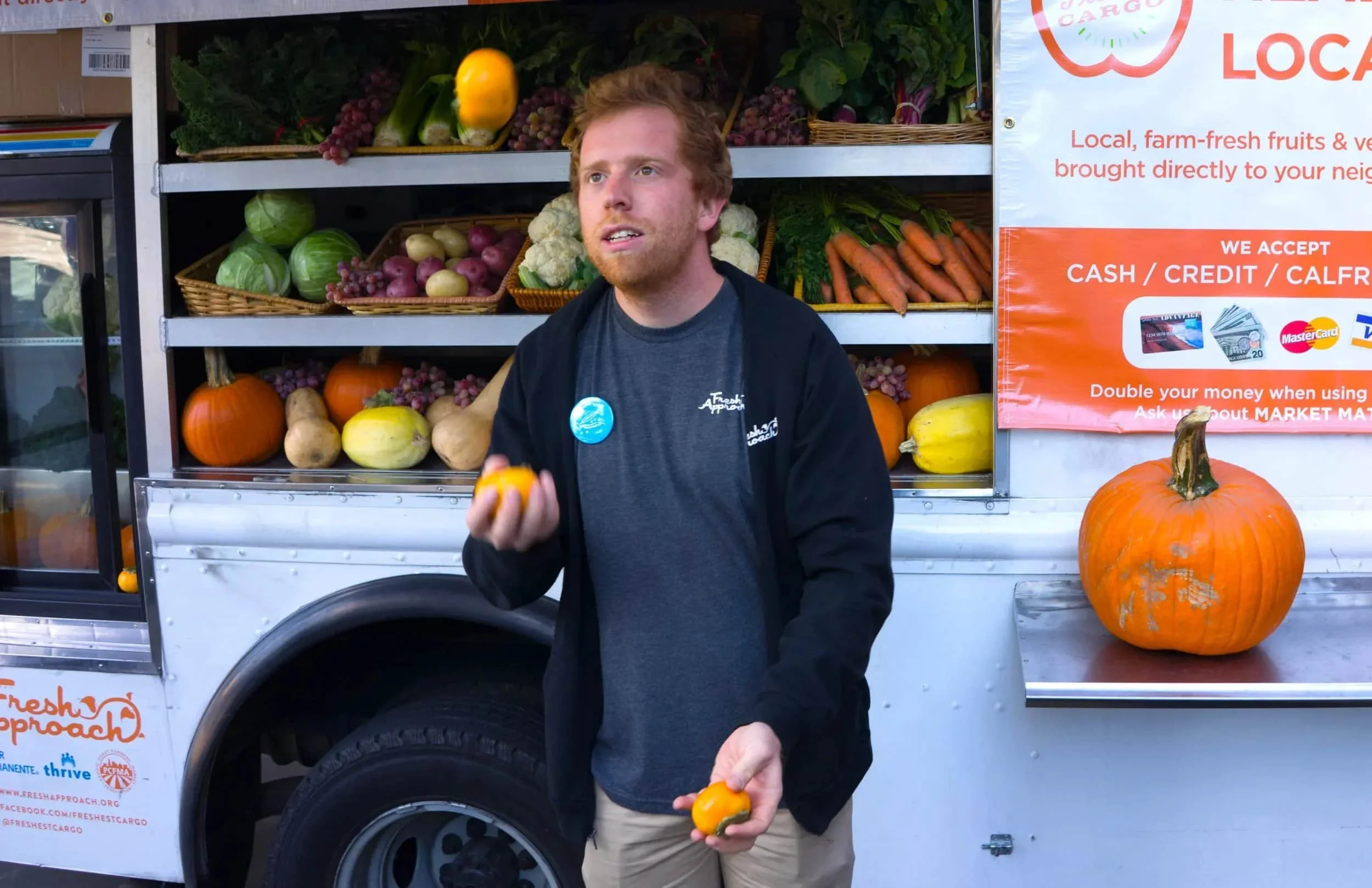 Andy Ollove juggling produce at a mobile market truck