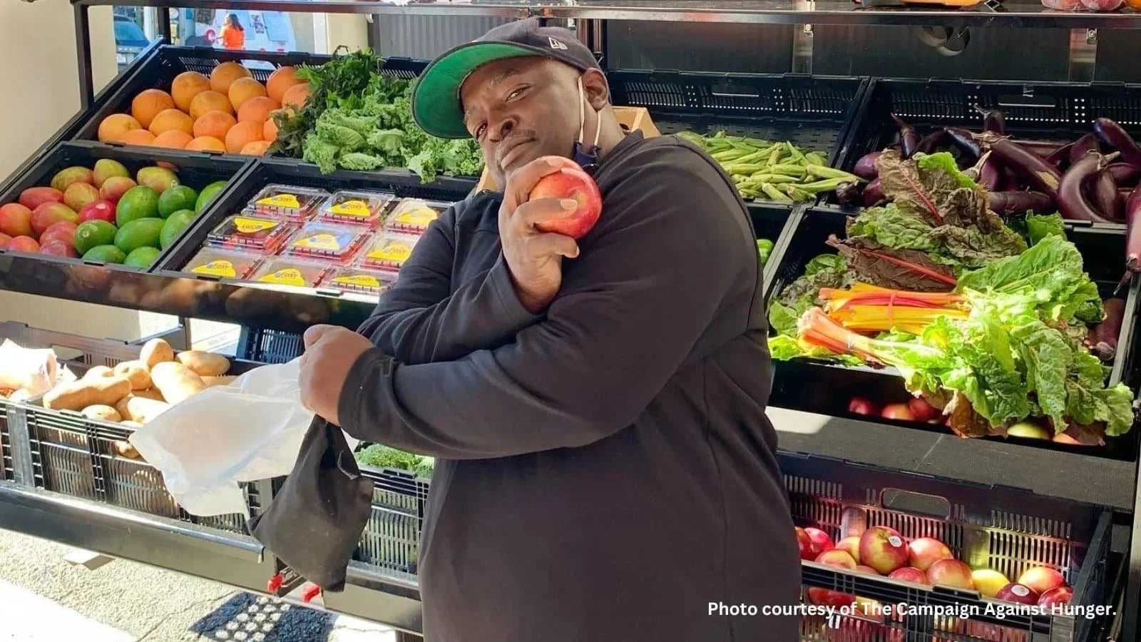 A community member poses with an apple in front of a mobile market