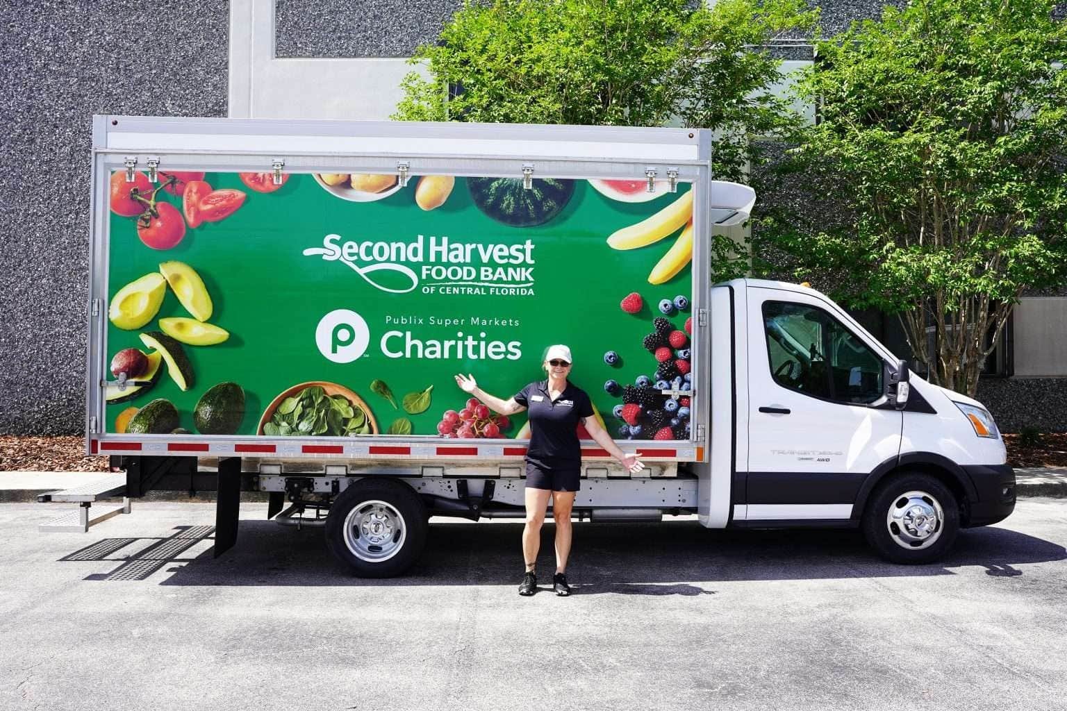 A person poses in front of a mobile market truck at the launch