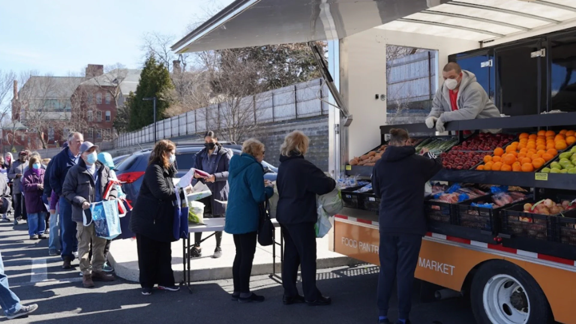 Community members line up to buy produce from a mobile market