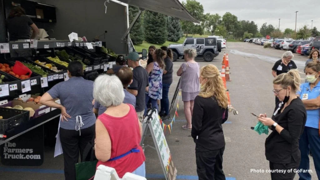 Community members stand in line to buy produce at a mobile market