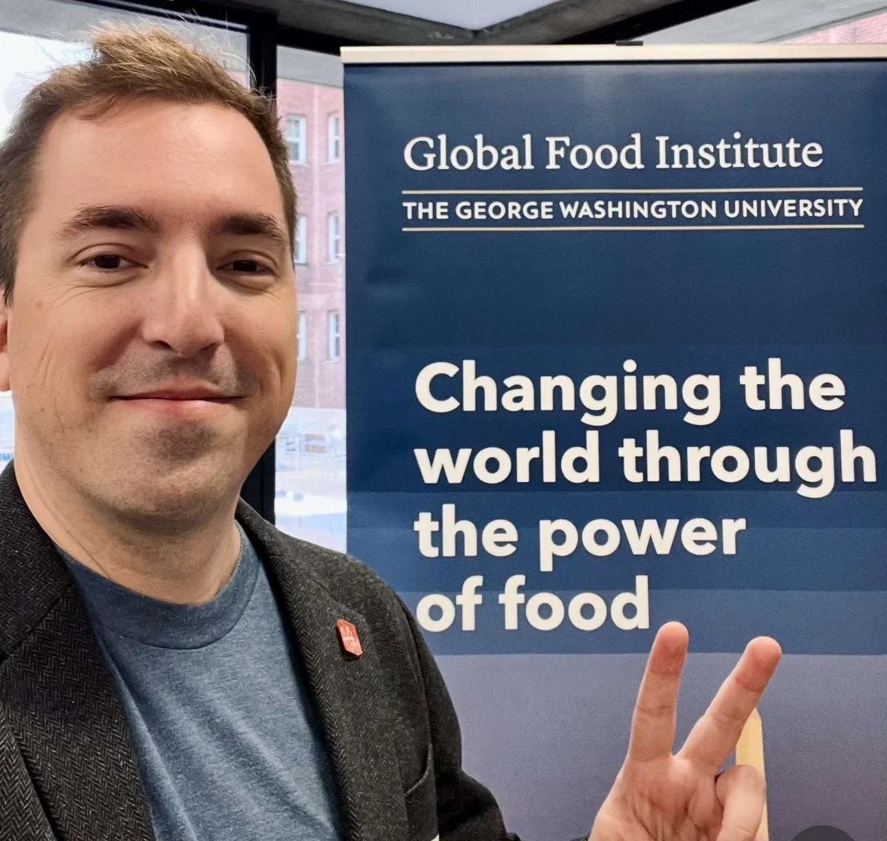 Fred posing in front of a banner for the Grocery Retail for All Summit