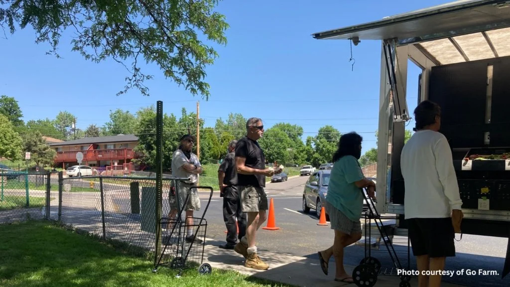 Community members stand in line at a mobile market truck