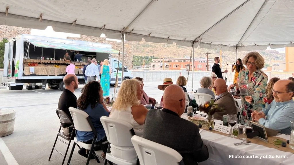 Community members sitting at a table and eating next to the GoFarm mobile market