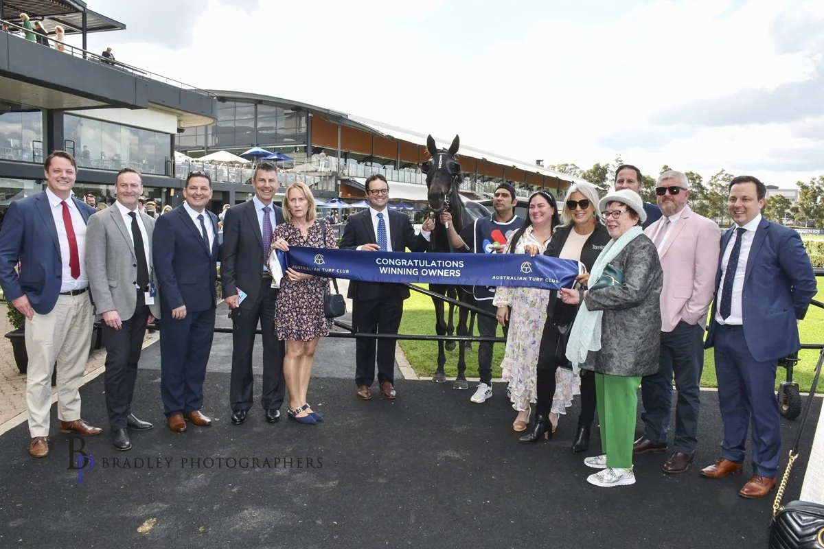 Tricolours Race Horse Syndicate owners with banner "CONGRATULATIONS WINNING OWNERS,".