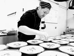 Chef garnishing dishes in a professional kitchen.