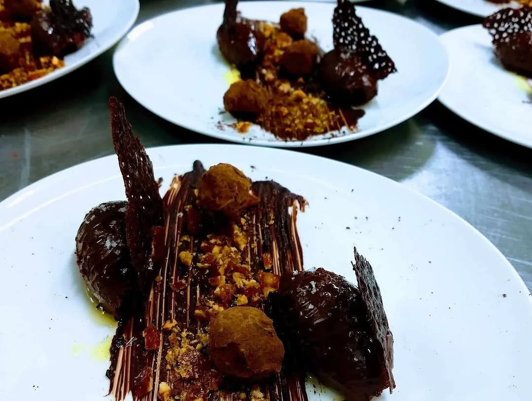 Chocolate dessert plates with truffles, garnished with crumbles and decorative chocolate pieces.