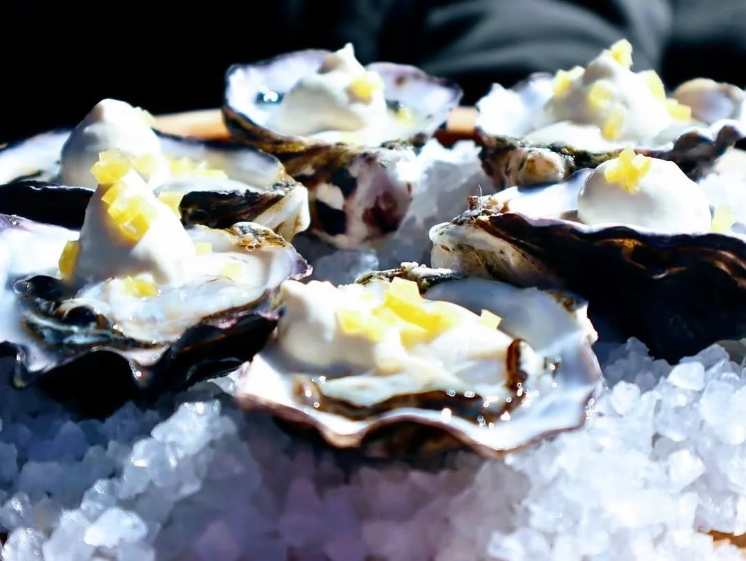 Fresh oysters on ice topped with lemon and sauce.
