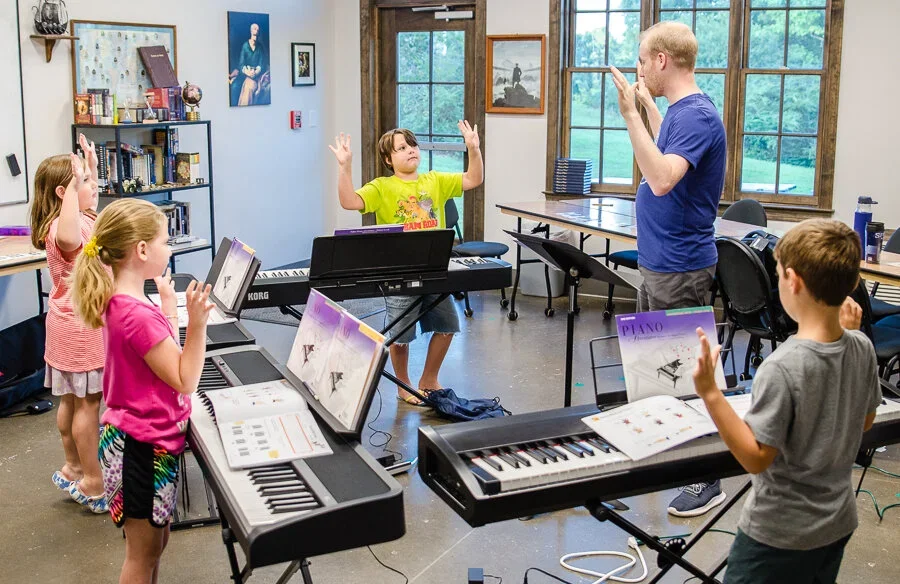 3 students standing behind pianos during a group class