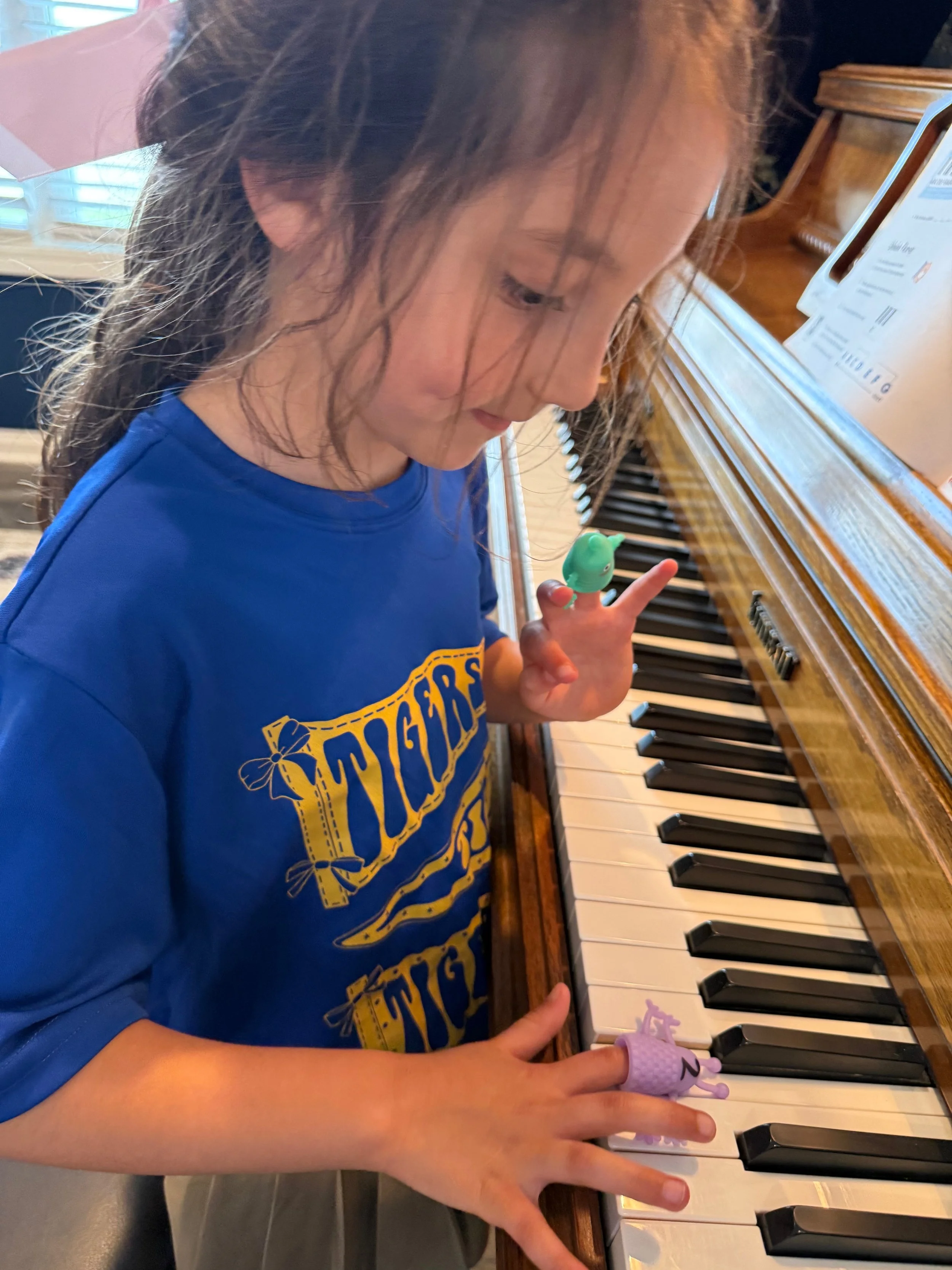 Piano teacher with small child in her lap sitting at the piano learning music. 
