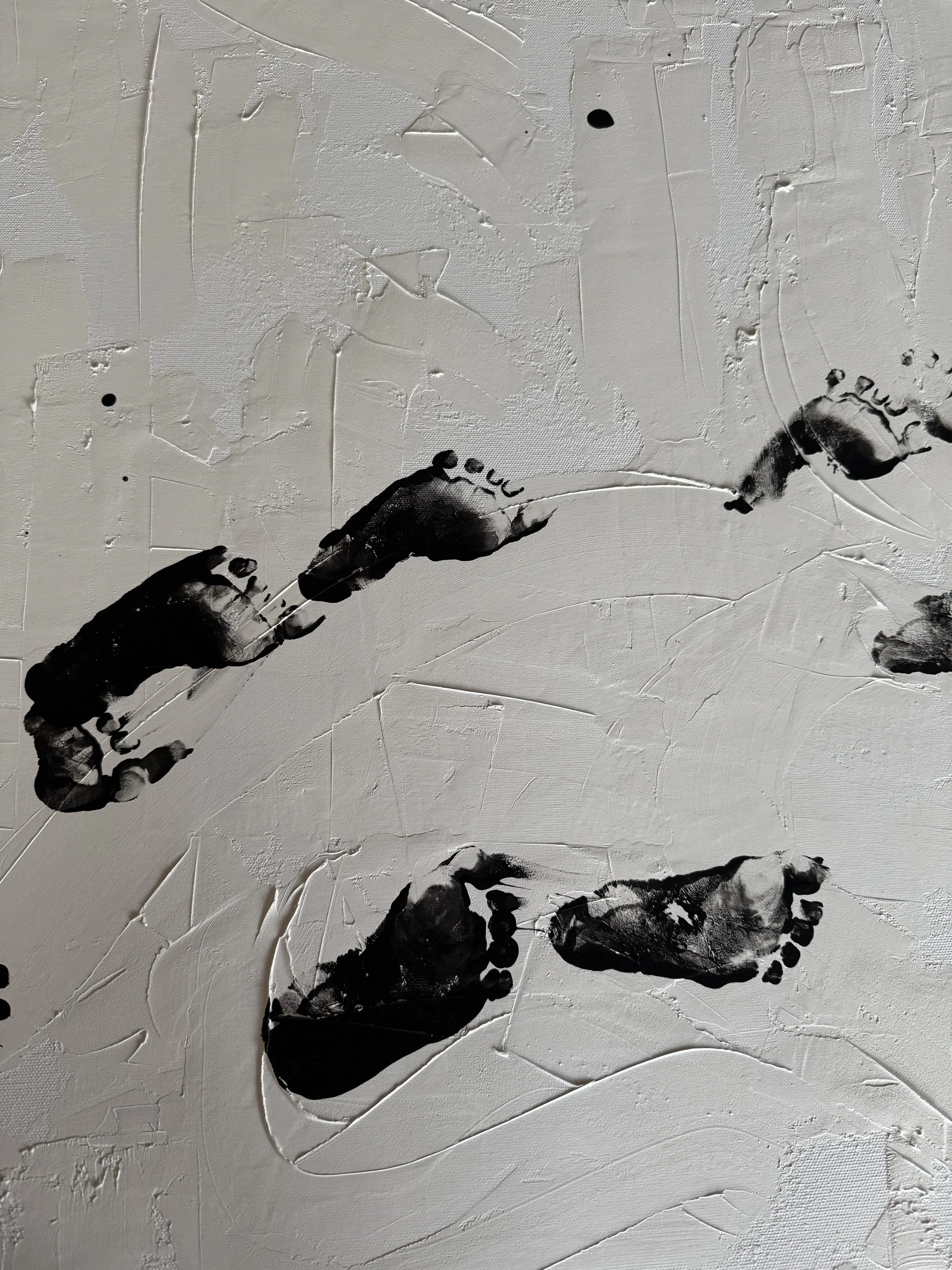 Black footprint art on a beige textured surface.