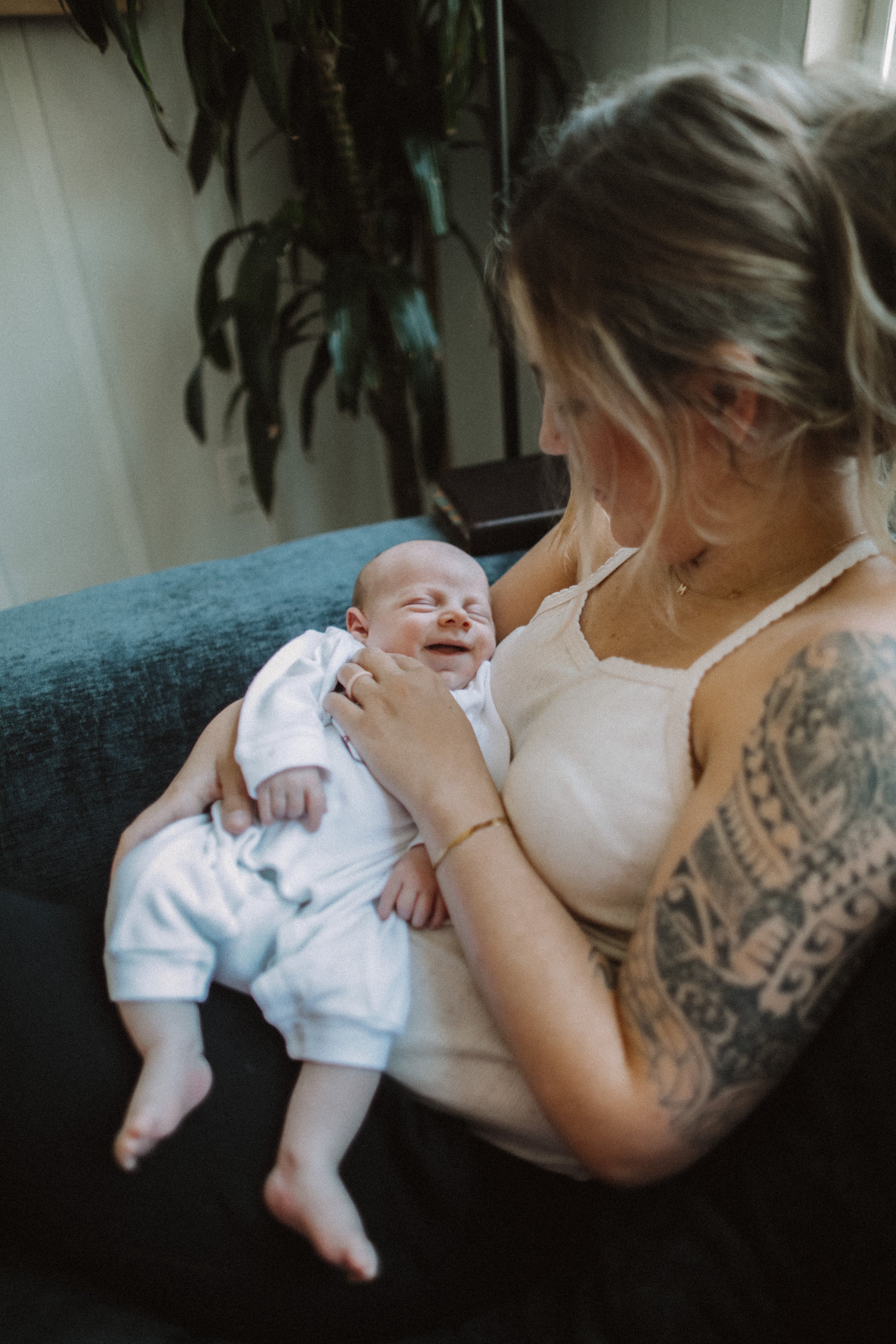 A woman holding a smiling baby on her lap on a couch at home.