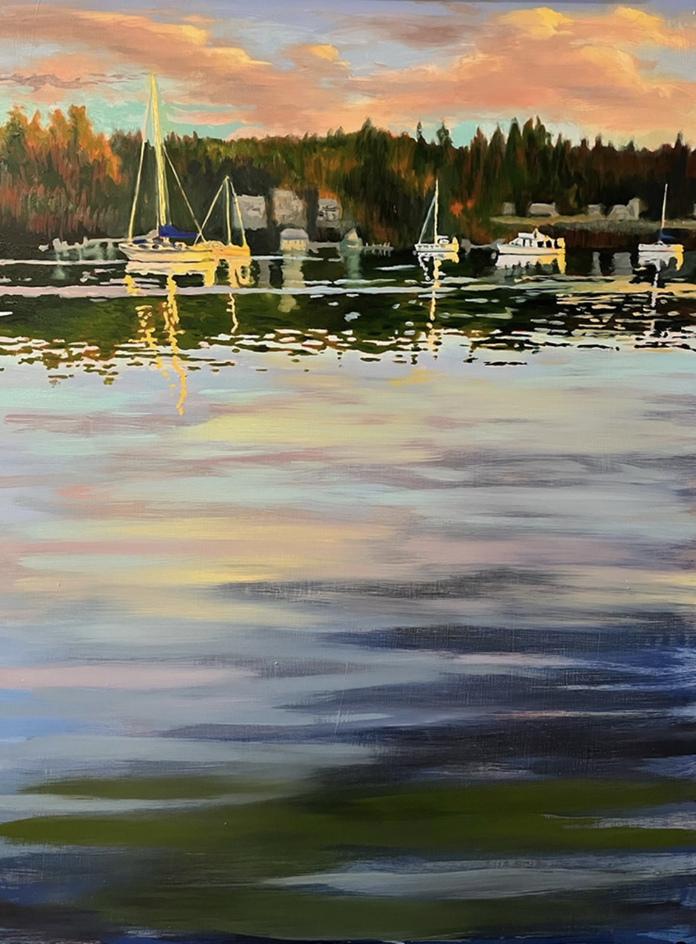 A watercolor painting of a lakeside scene at sunset featuring several sailboats and motorboats docked near the shore, with forested land and houses in the background, and colorful sky reflected in the water.