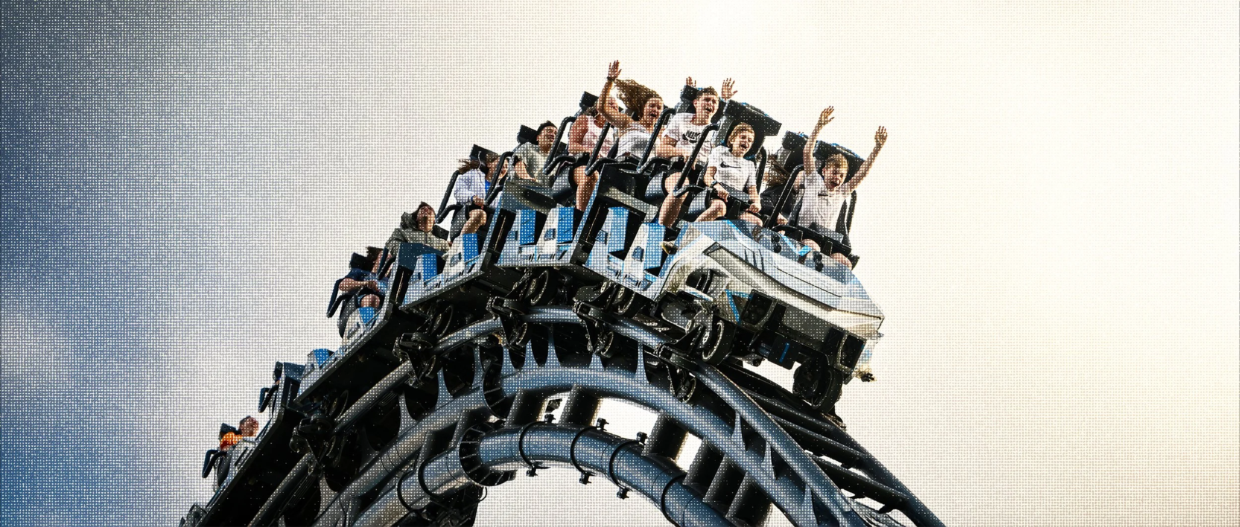 Riders on Velocicoaster at Universal Islands of Adventure raising their hands against a bright sky.