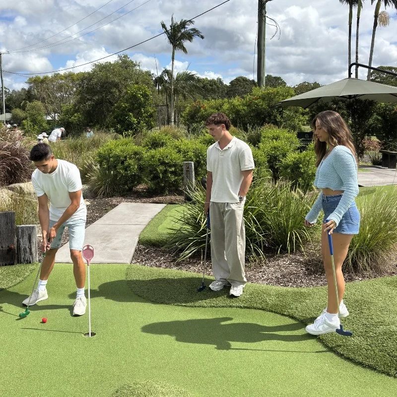 3 people playing mini golf