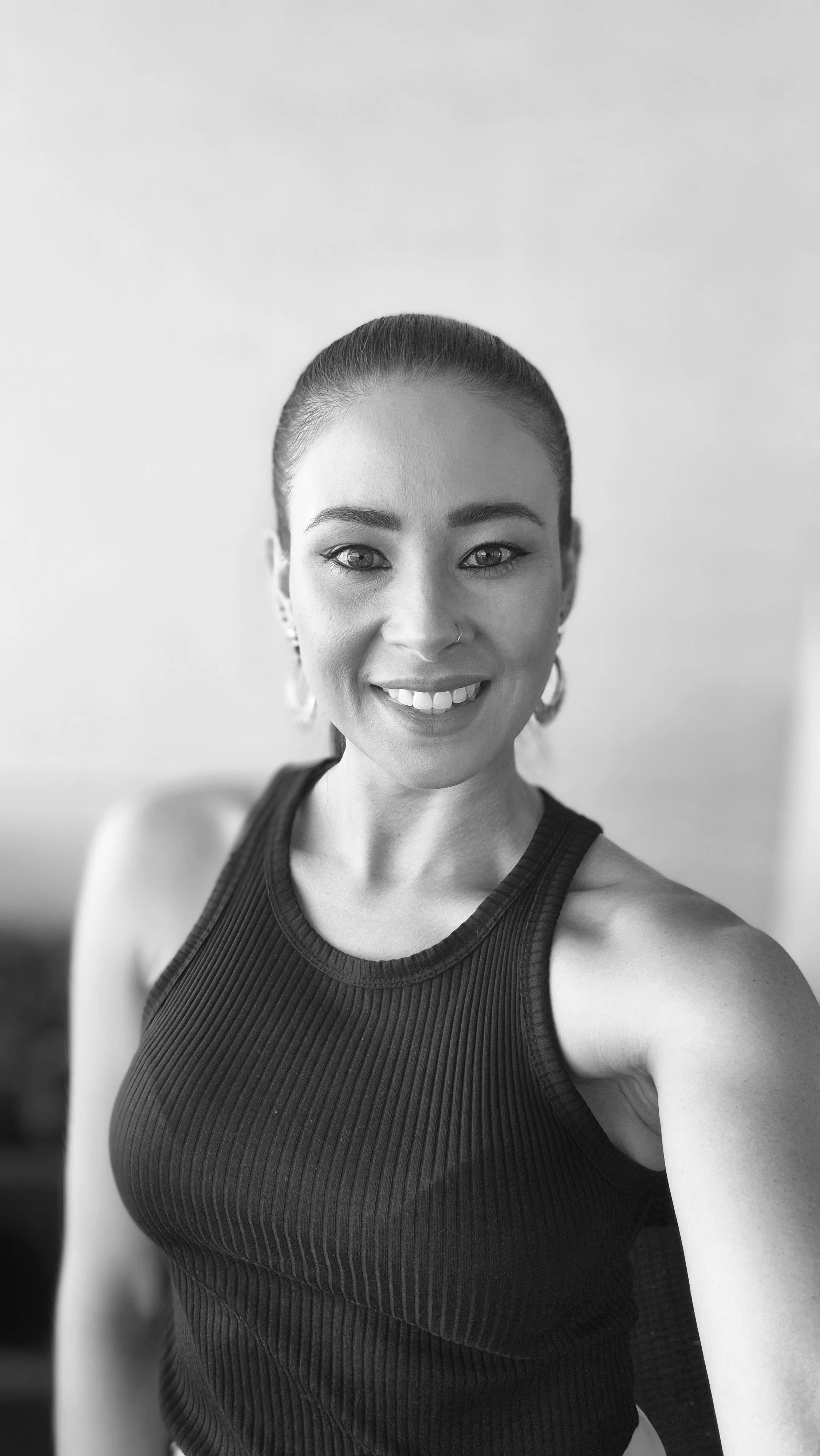 Hospitality interior design. Restaurants, bar and cafes. Black and white photo of Kimberly Evans, wearing a sleeveless top, with her hair pulled back.