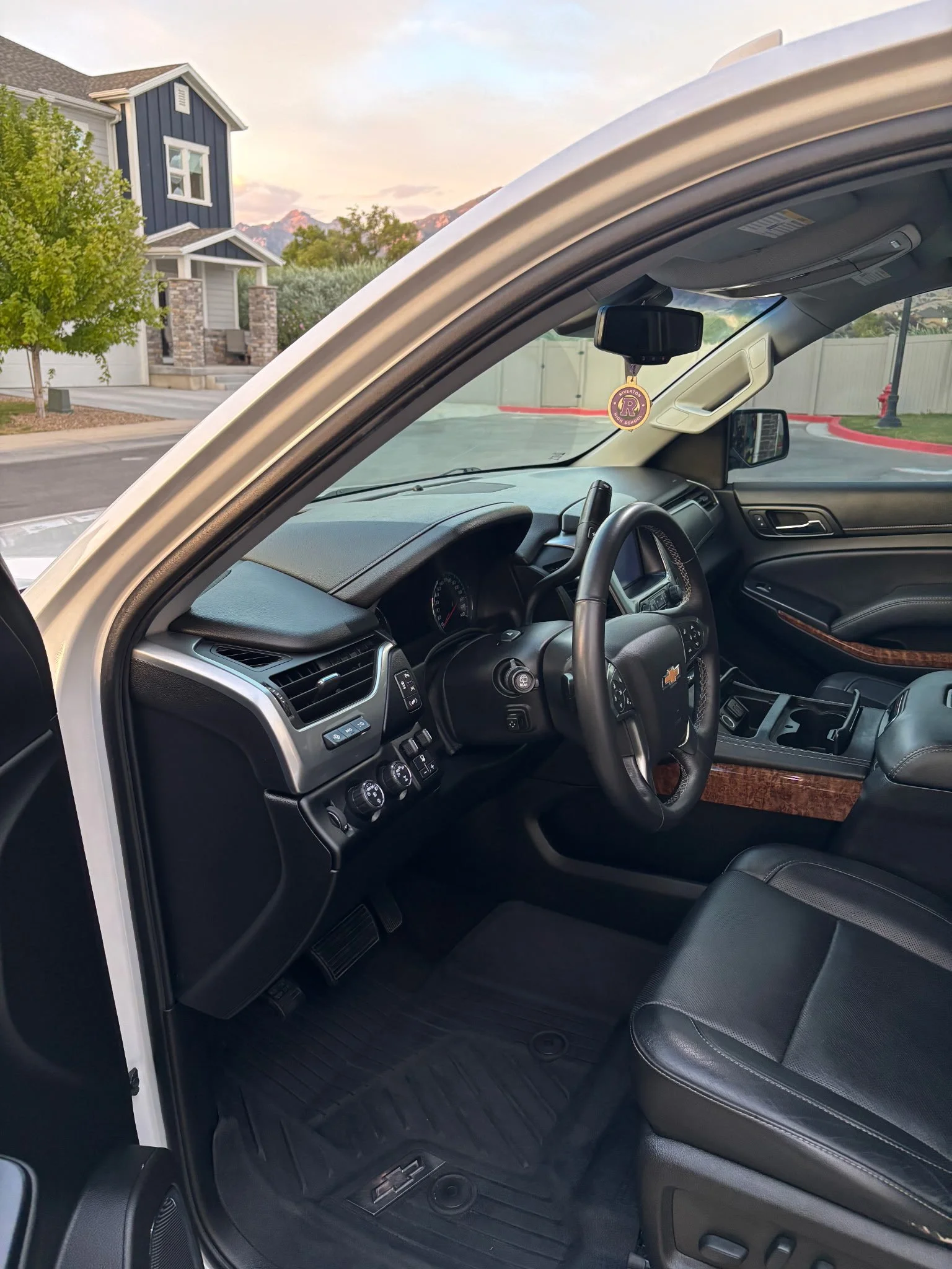 Interior of a Chevrolet vehicle showing the dashboard, steering wheel, and front seat, with a view of a residential neighborhood outside.