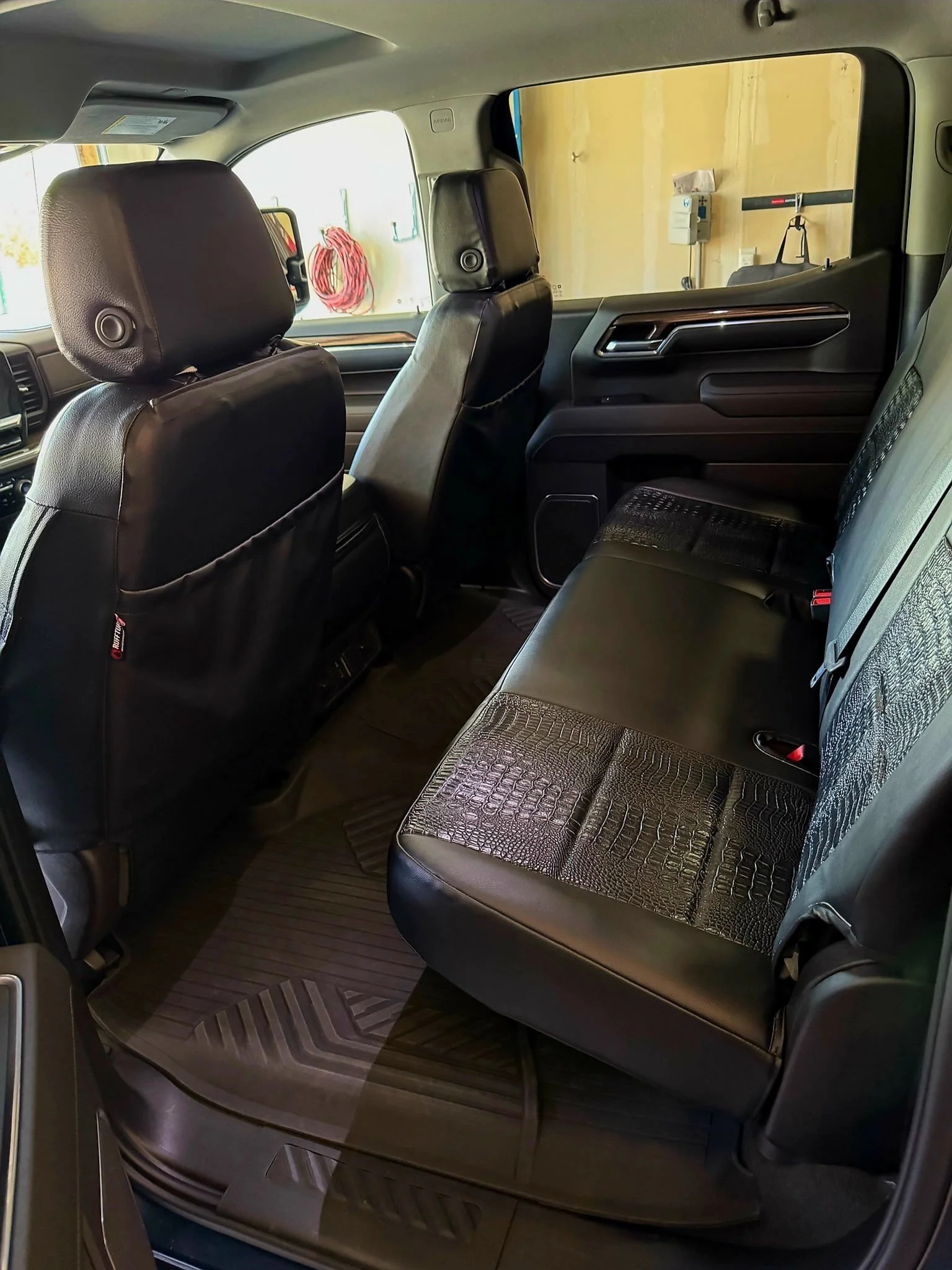 The interior of a vehicle showing the back seats, front seats, and part of the driver's side window.