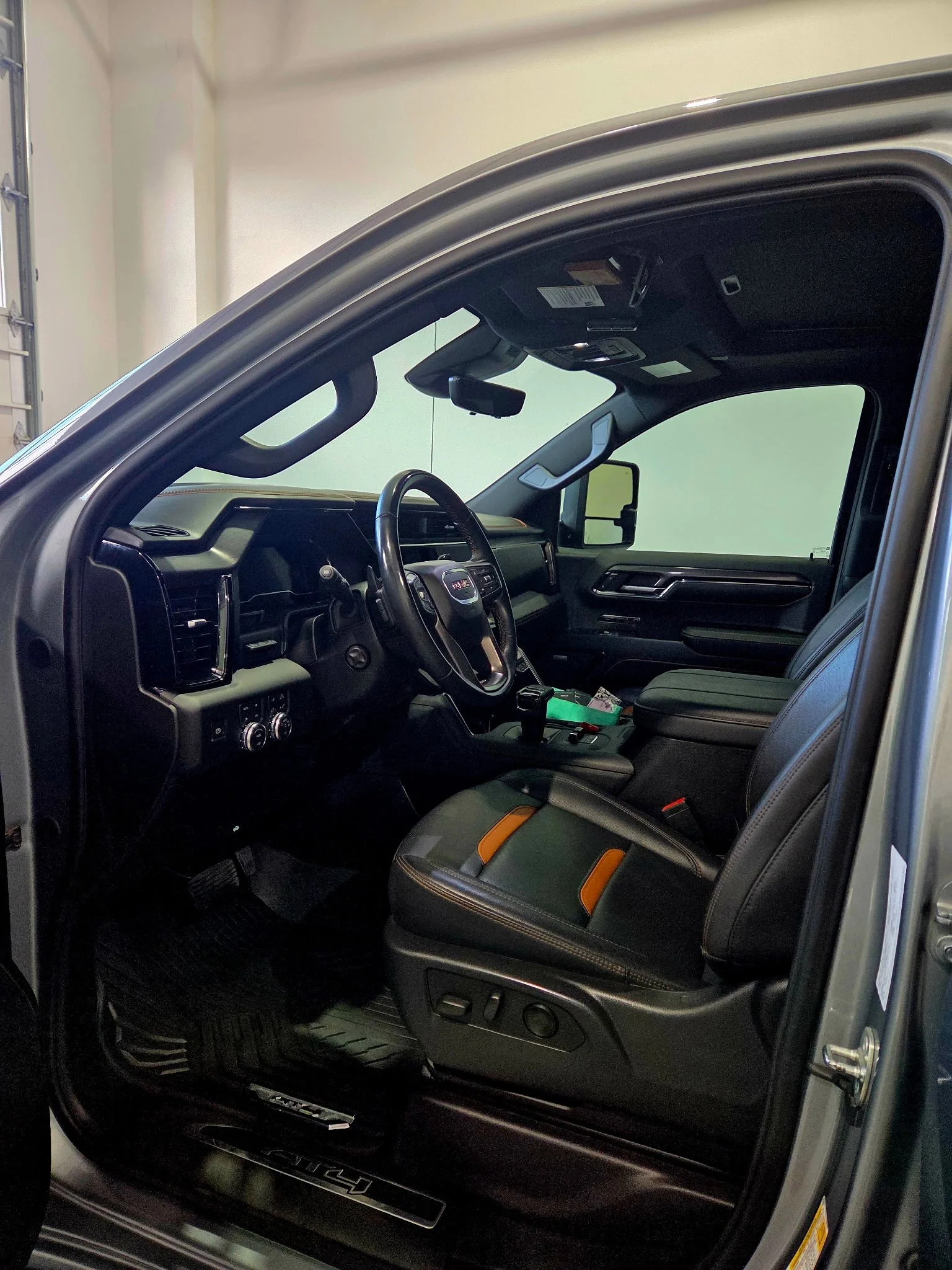 Interior of a black GMC truck with a leather seat and dashboard visible.