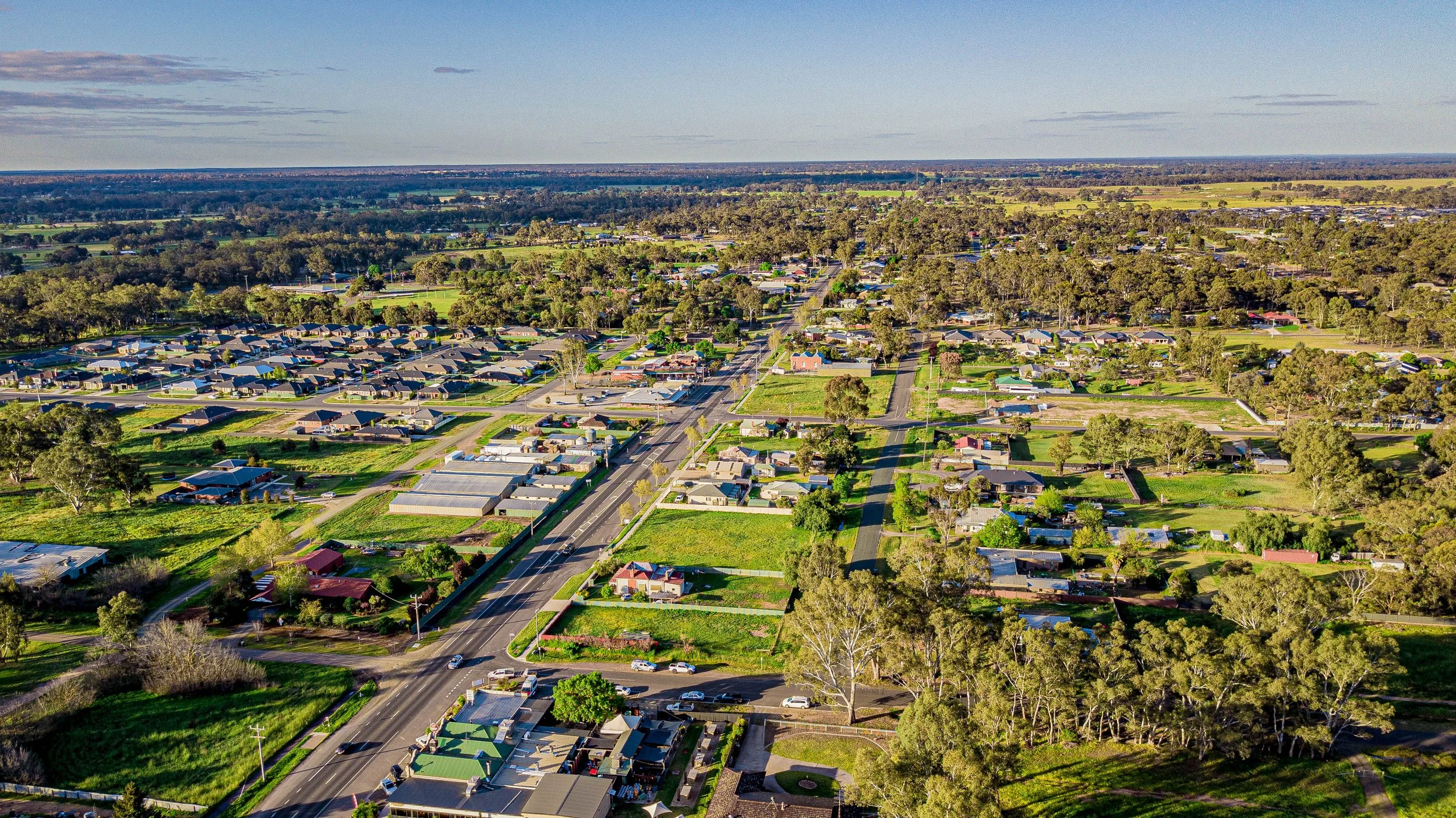 A landscape with snow-capped mountains in the background and rolling grassy hills in the foreground. There is a modern building on the hillside.