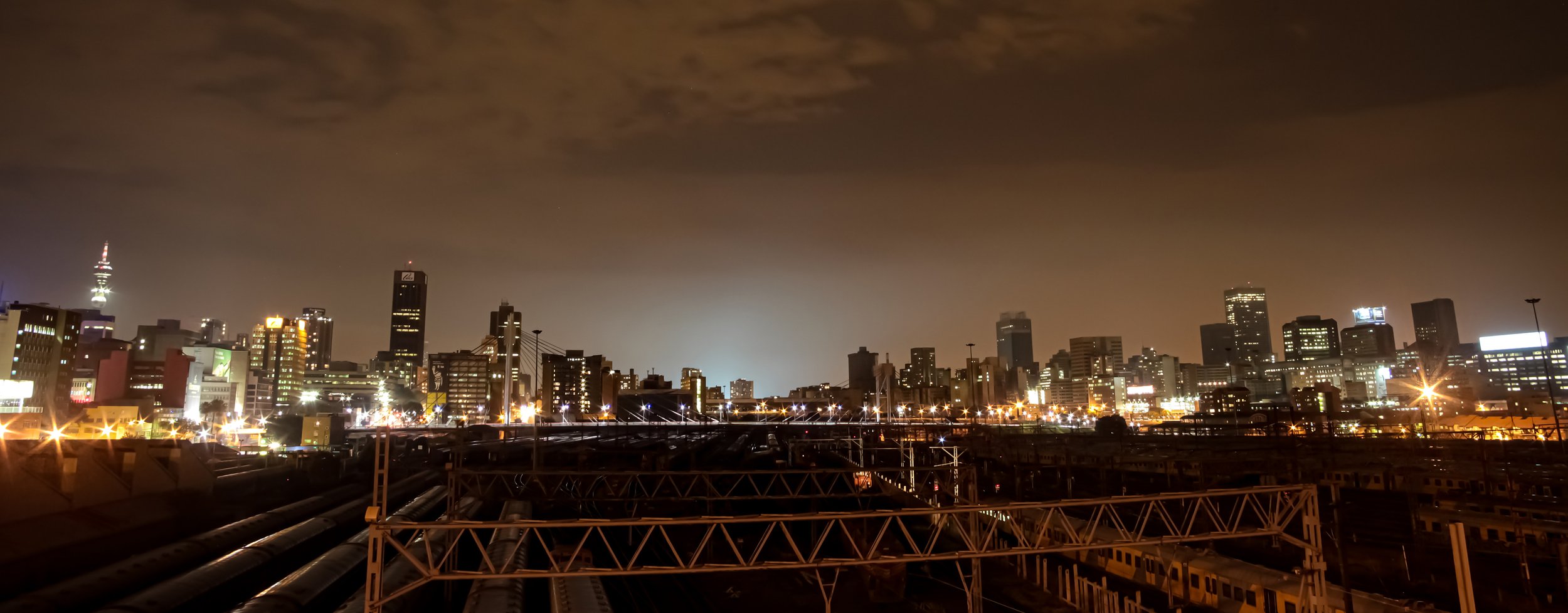 Night time view of commuter trains under Nelson Mandela Bridge in Braamfontein Johannesburg CBD by Gestaldt
