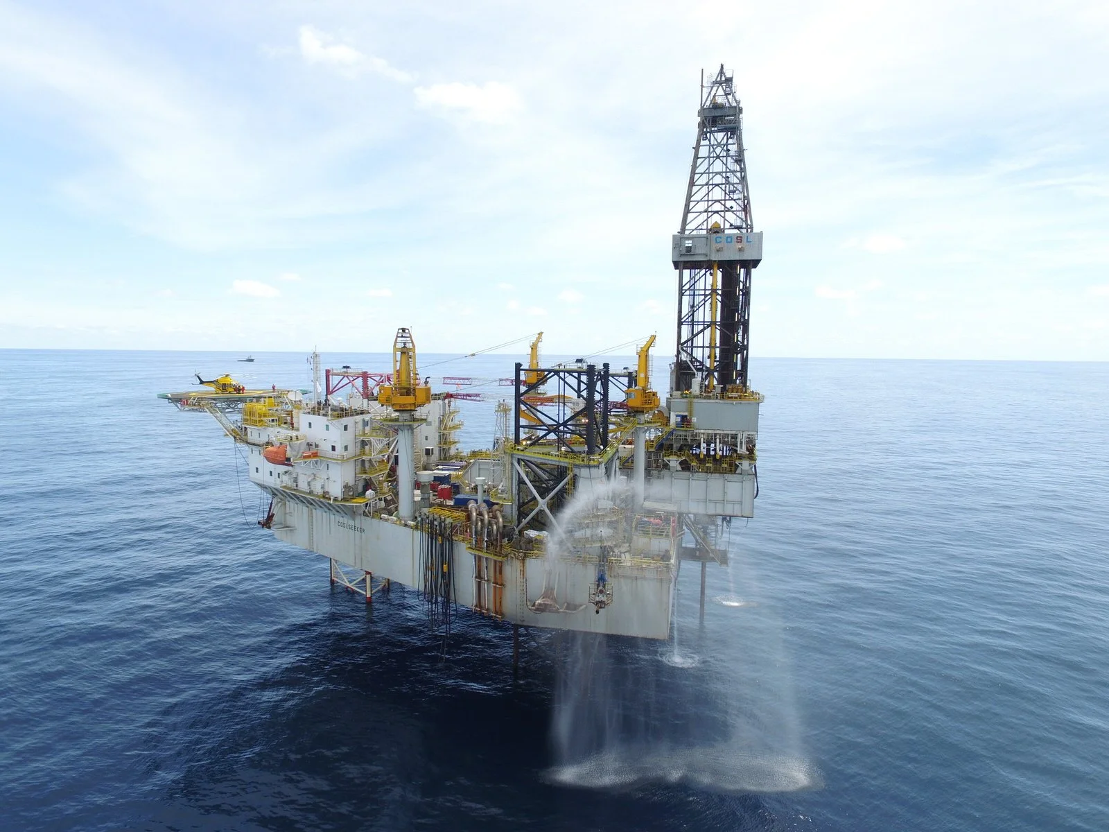 Offshore oil drilling platform in the ocean with a helicopter flying nearby.