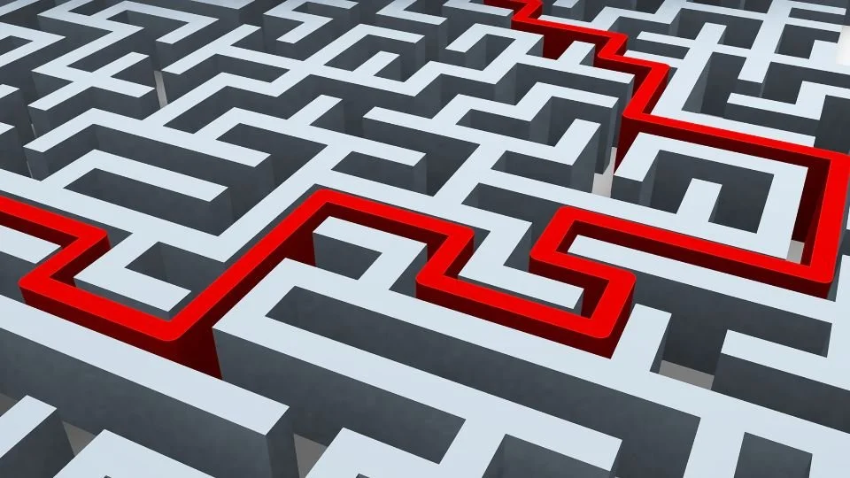 A three-dimensional maze with white walls and a red path highlighting the route through the complex pathways.