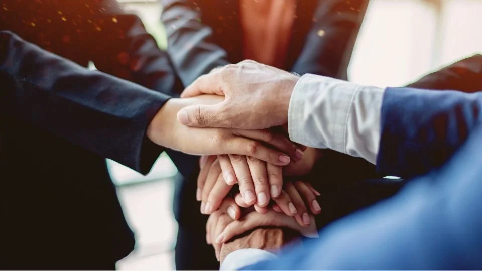 Group of people with hands stacked together in a gesture of unity or teamwork.
