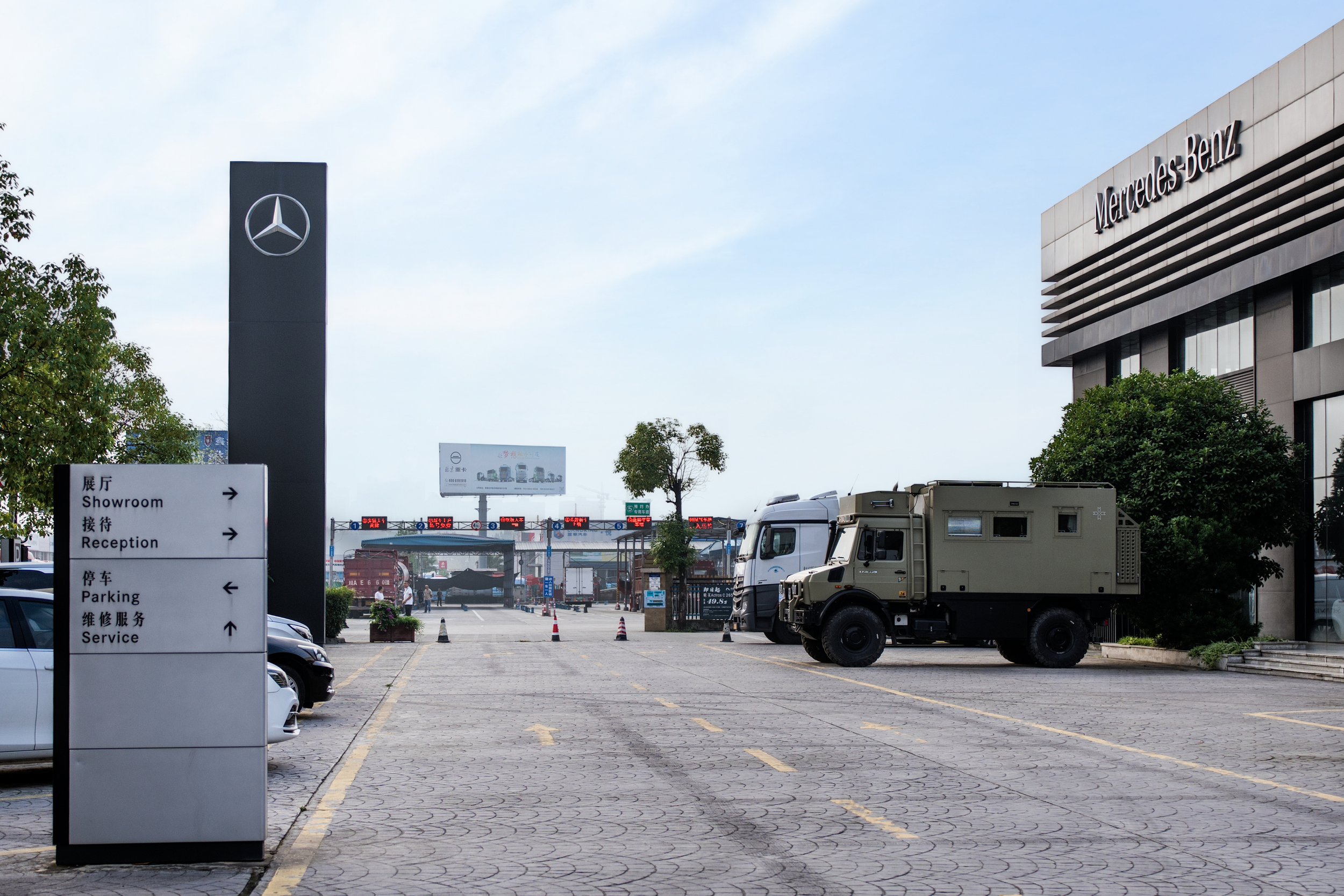 Mercedes-Benz dealership parking lot with trucks, signage, and building in the background.