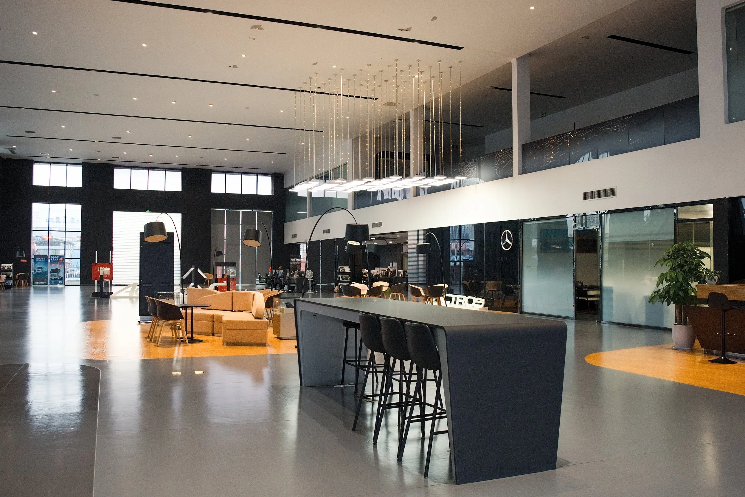 Modern, spacious car dealership showroom with high ceilings, large windows, and a variety of seating and display areas.