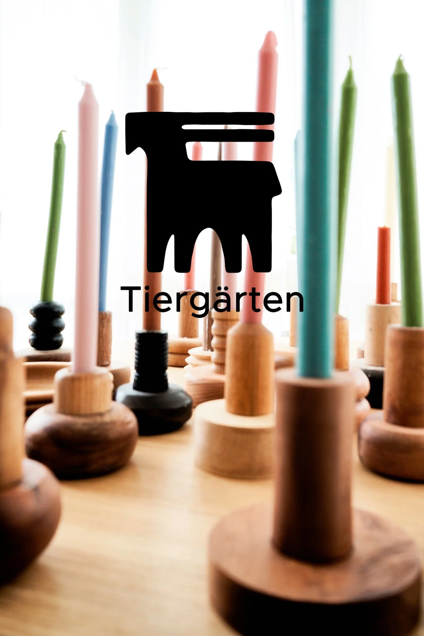 Schwarz silhouettierte Hundelogge vor einer Reihe bunter Kerzen, mit dem Text 'Tiergärten' darunter.