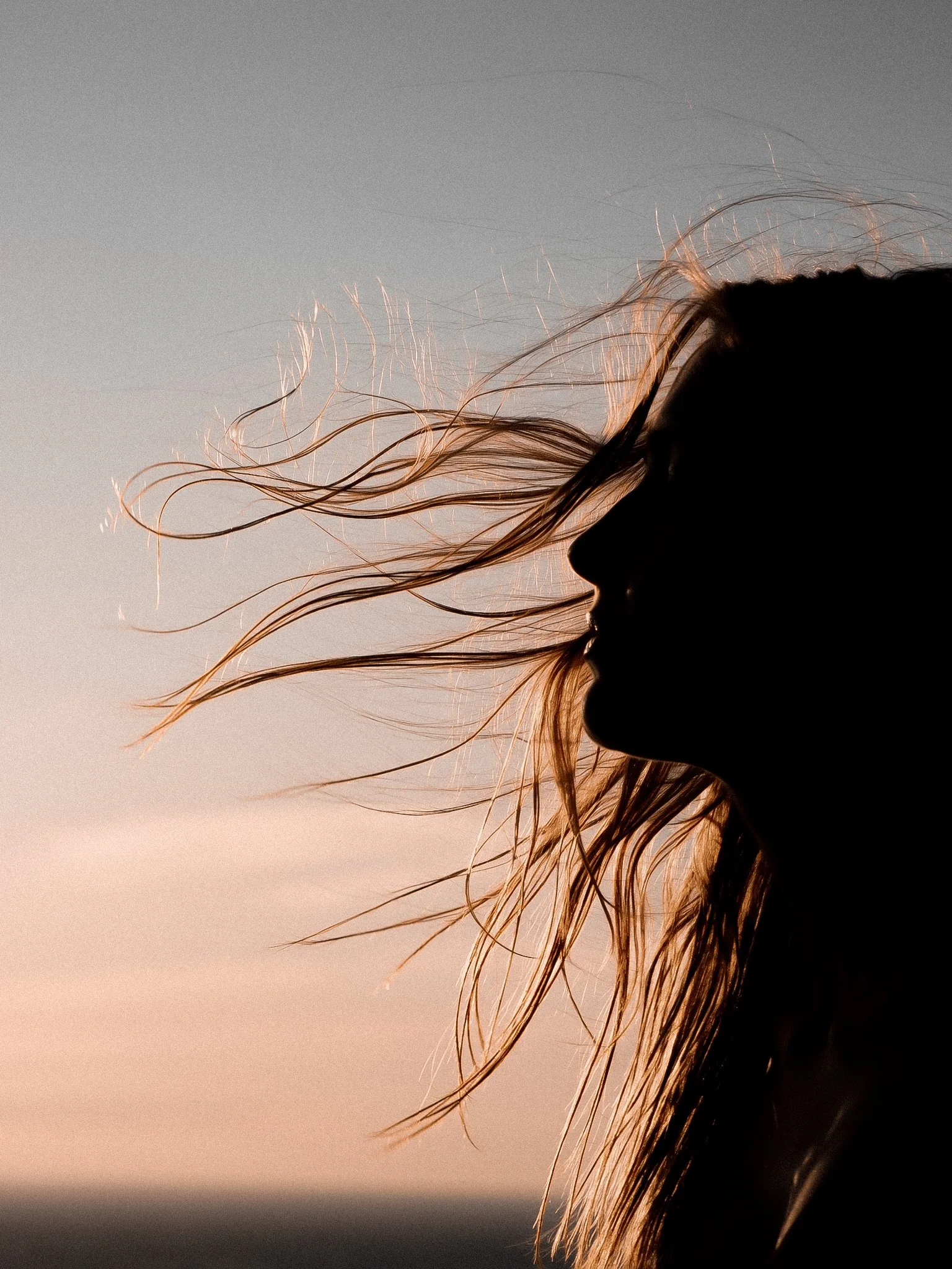 Woman at sunset with hair blowing in the wind