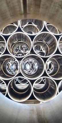 Multiple large metal pipes arranged vertically inside a cylindrical structure with glowing lights along the edges of the pipes.