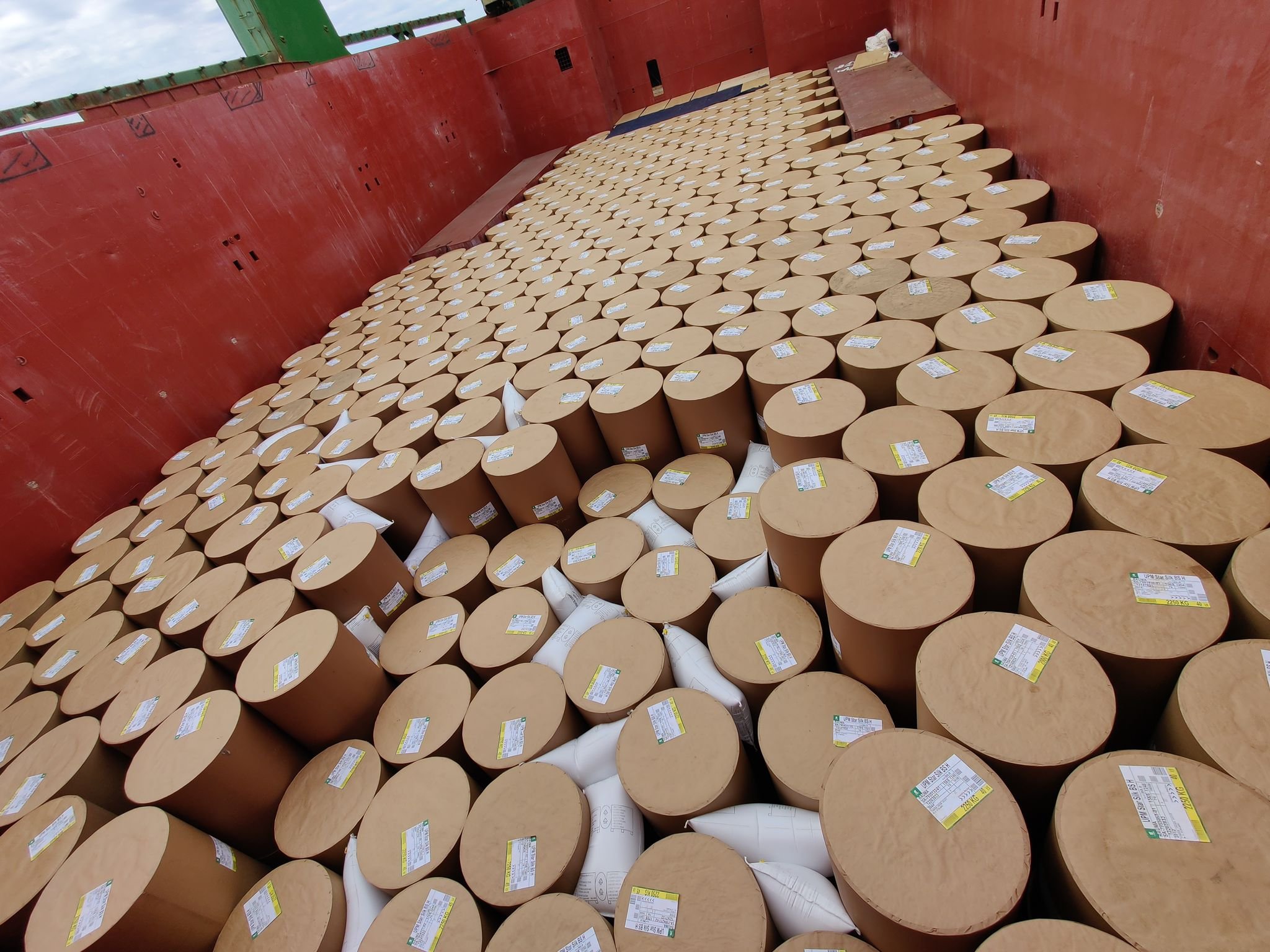 A large number of cardboard tubes stacked in the back cargo ship. Each tube has a label on top.