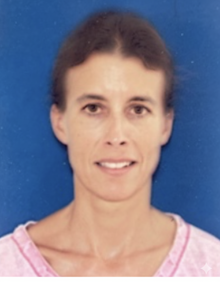 A woman with short brown hair smiling in front of a blue background, wearing a pink top.