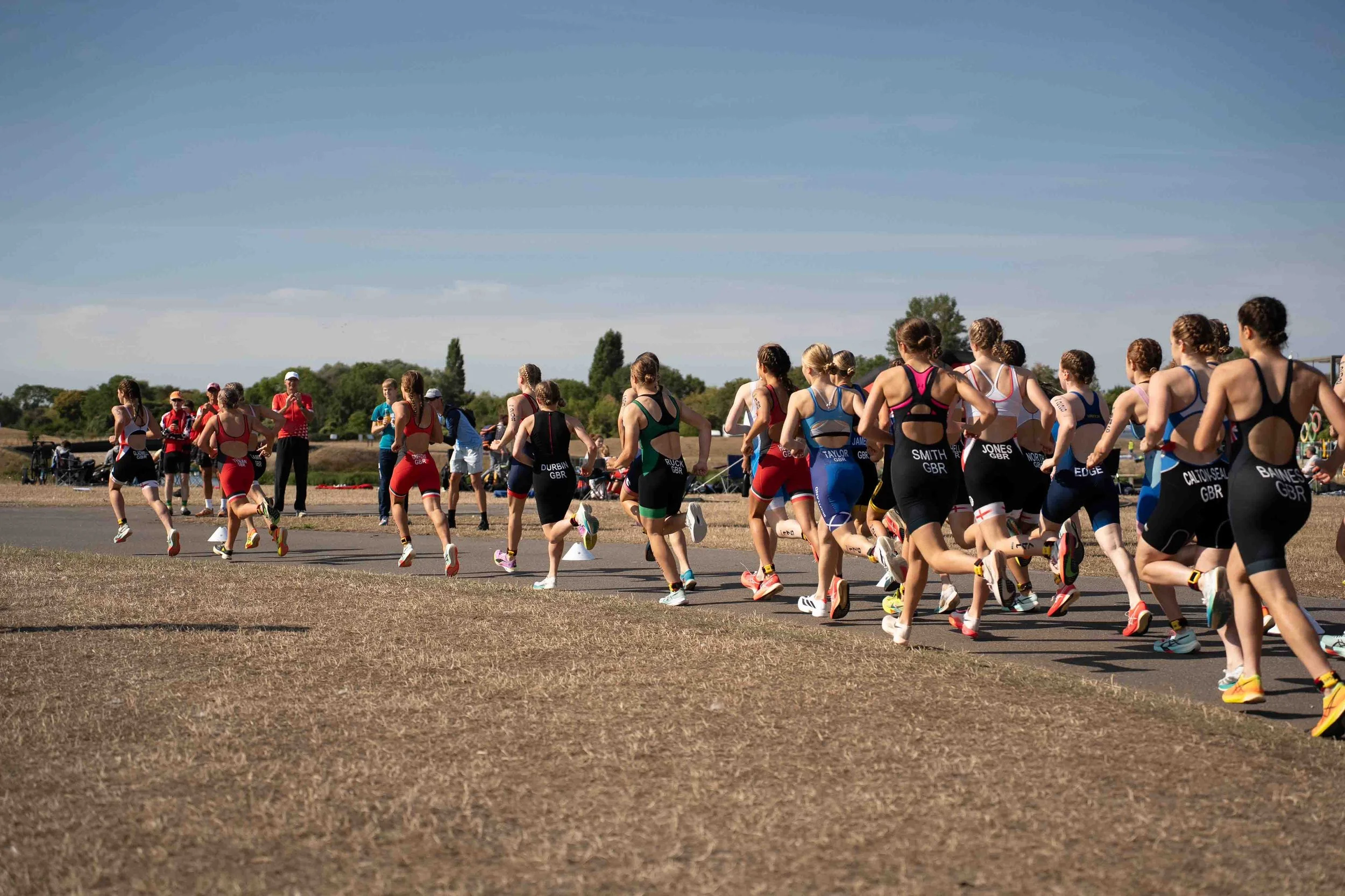 Group of female runners participating in a race outdoors on a sunny day.