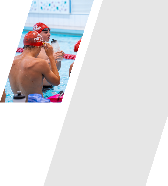Swimmers in a pool wearing red swim caps, preparing for a race or training session.