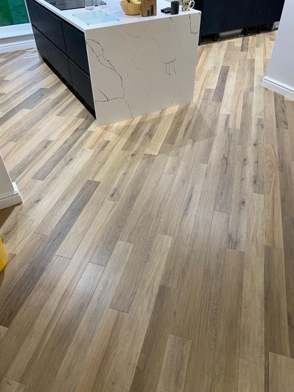 Wooden floor in a kitchen with a white marble island and black cabinets