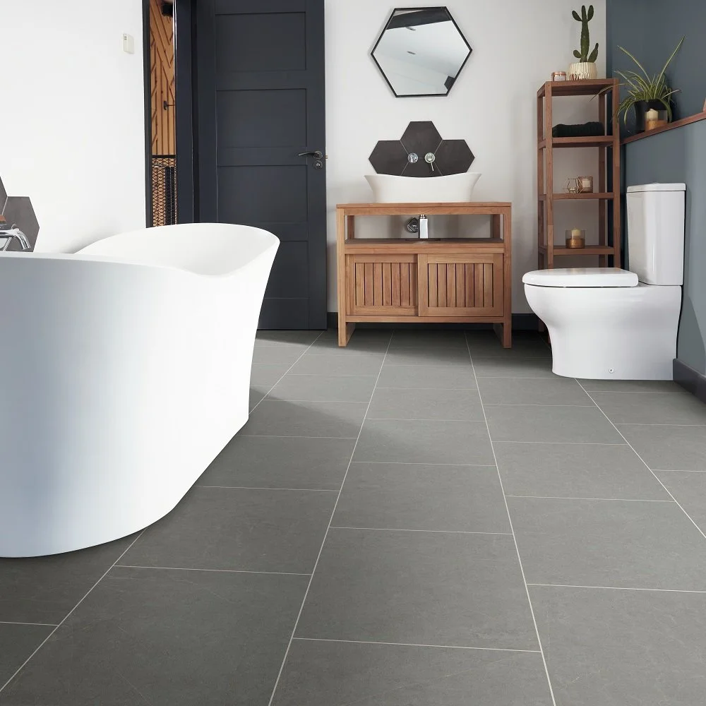 Modern bathroom featuring a white bathtub, a wooden vanity with a vessel sink, a black door, a toilet, a tall wooden shelf with plants and decor, and hexagonal mirrors on the wall.