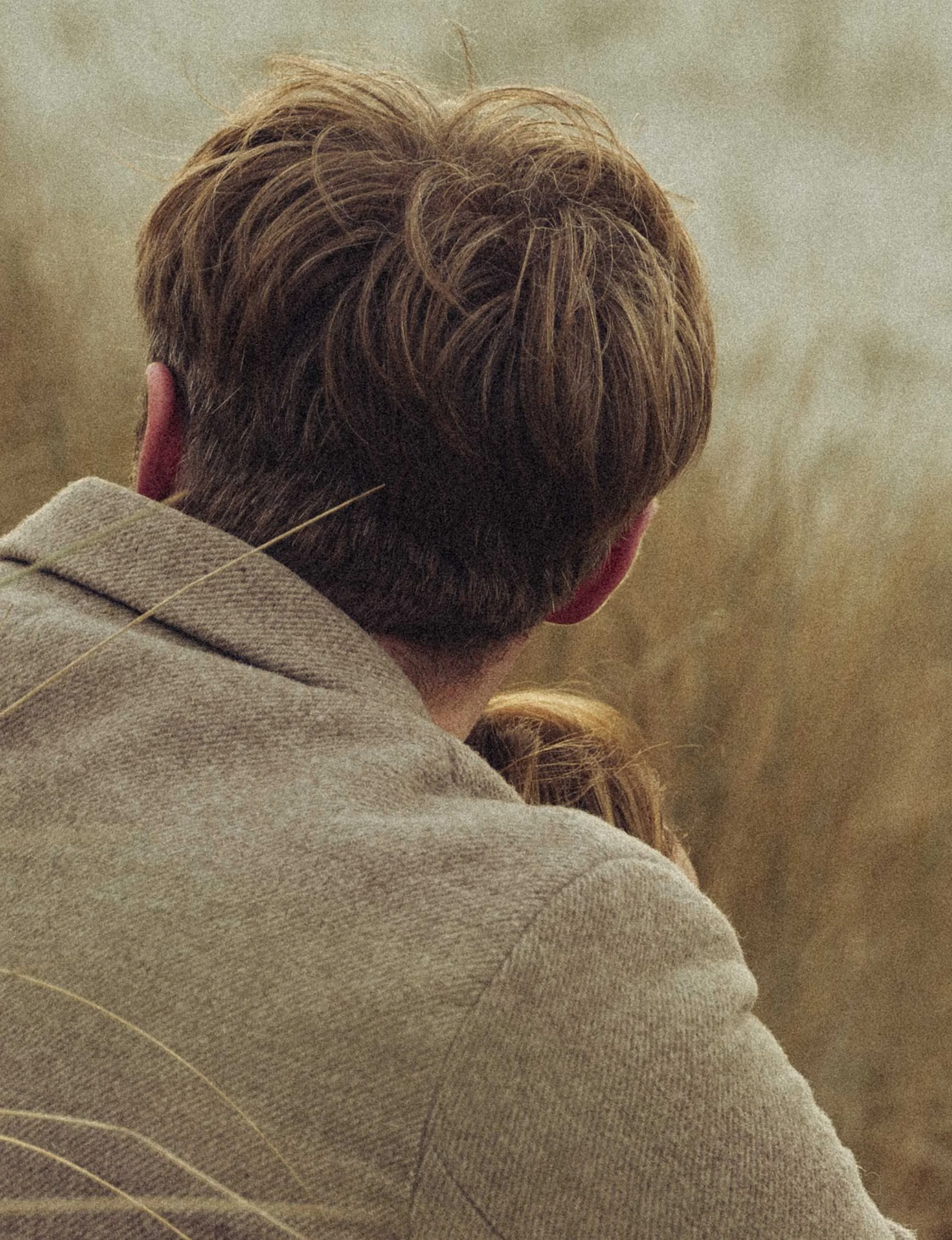 Stel knuffelt elkaar tijdens een ontspannen fotoshoot op een landelijke locatie.