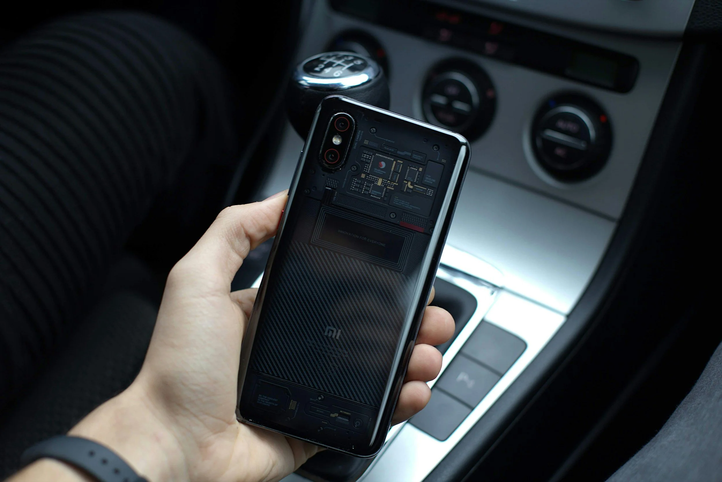 Hand hält ein Smartphone im Carsharing-Auto oder in einem Ridehailing-Auto.