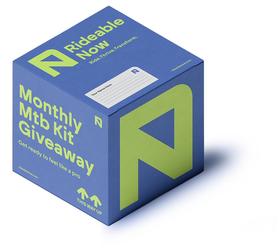 Blue and green box labeled 'Rideable Now' for a monthly mountain bike kit giveaway, with text 'Get ready to feel like a pro' and arrows pointing up labeled 'This Way Up'.